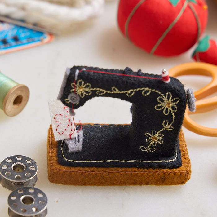 Hand-felted antique sewing machine ornament with gold embroidery and tiny thread spool, handmade by women artisans