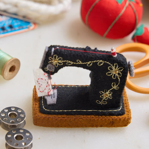 Hand-felted antique sewing machine ornament with gold embroidery and tiny thread spool, handmade by women artisans