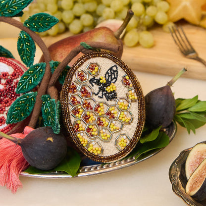 Fair trade beehive ornament featuring delicate beadwork and embroidered bee in flight
