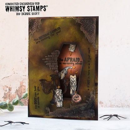 A handmade Halloween card featuring a coffin-shaped cutout with layered spooky elements, including candles with faces, candlesticks, and a dark, textured background. There are scattered sentiments including 'Be AFRAID... be verrrrry afraid'