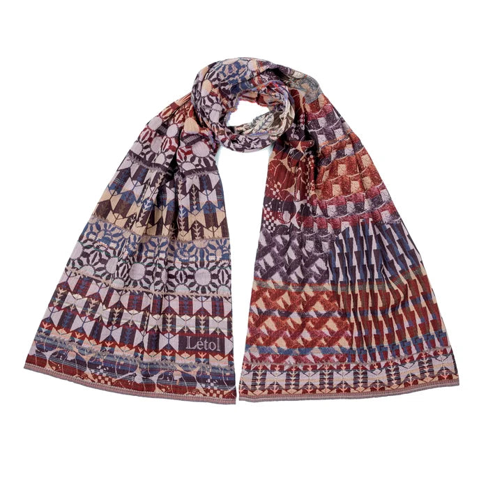 Létol Come Scarf in Cassis, looped and laid flat against a white background showing both sides simultaneously — one side featuring a bold geometric Art Deco pattern of repeating chevrons, medallions, and stylized floral rosettes in blackcurrant, violet, and mauve on a dusty rose ground with the woven Létol signature, the other showing a densely interlaced diagonal lattice and chevron pattern in russet, burgundy, and purple with khaki accents