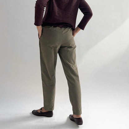 Back view of model wearing the Bryn Walker Corduroy Boslow Pants in Jasper, showing elastic waistband, relaxed tapered leg, ankle length, and olive jasper pinwheel corduroy, styled with burgundy Double Cotton Tee and brown Mary Jane flats