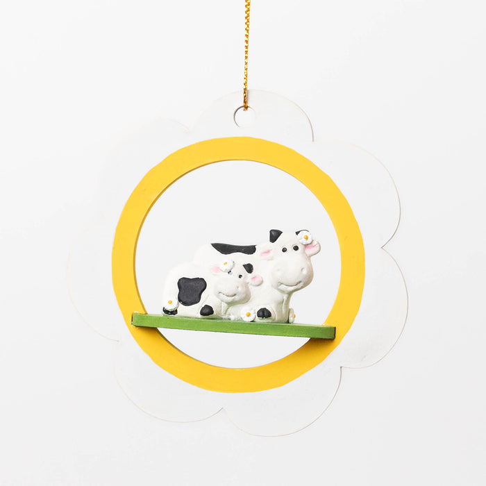 Rustic cow ornament showing tender moment between mother and calf on daisy flower