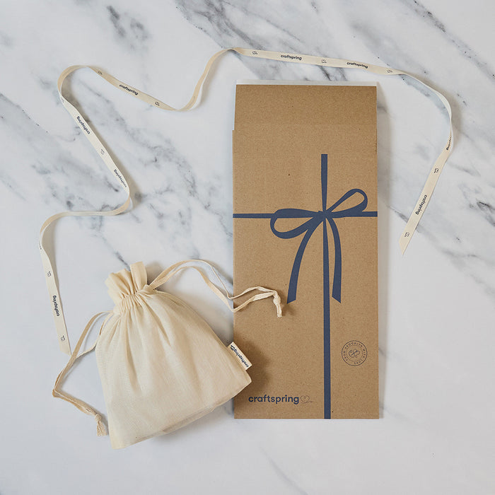Craftspring packaging for Santa Walrus Ornament, featuring a branded mailer and protective cloth bag displayed on a marble surface — ready to safely deliver heirloom-quality felt decor, ethically crafted by artisans using sustainable wool.
